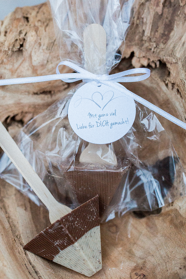 Eingeschmolzene Schokolade kann auch schön verschenkt werden. Die Schokolade wurde geschmolzen und mit einem Holzstil versehen. In einer durchsichtigen Verpackung, mit Schleife und Anhänger wirkt dieses Geschenk sehr herzlich. 