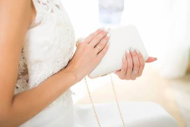 Braut hält eine weiße Handtasche in ihren Händen