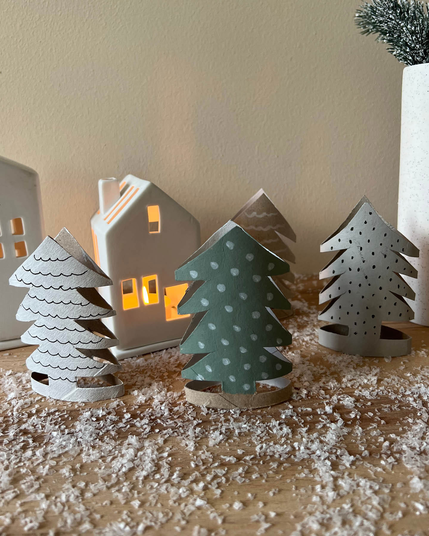 Tannenbäume aus Klopapierrollen stehen als Weihnachtsdeko auf einer Kommode