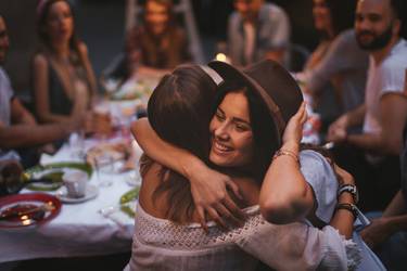 Zwei Freundinnen umarmen sich bei einer Geburtstagsparty