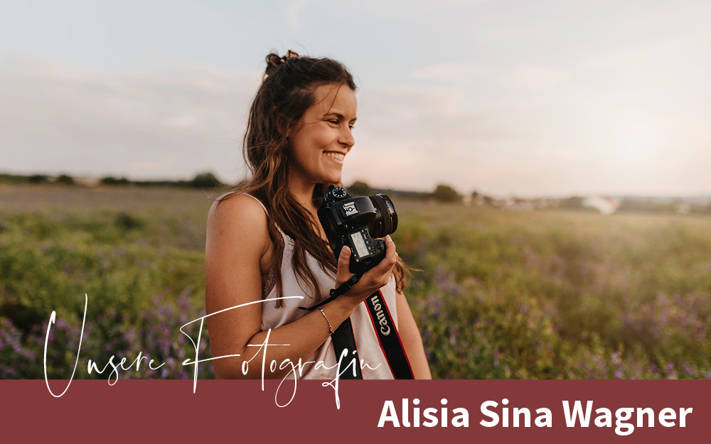 Fotografin Alisia Sina Wagner auf einem Feld, lachend mit Kamera