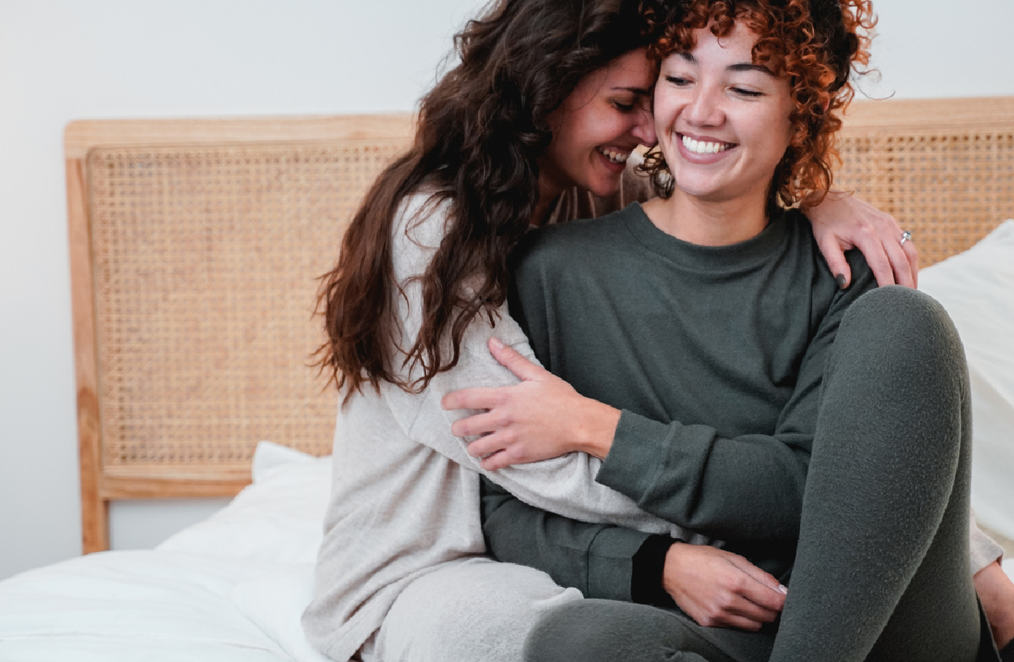 zwei Frauen umarmen sich auf einem Bett