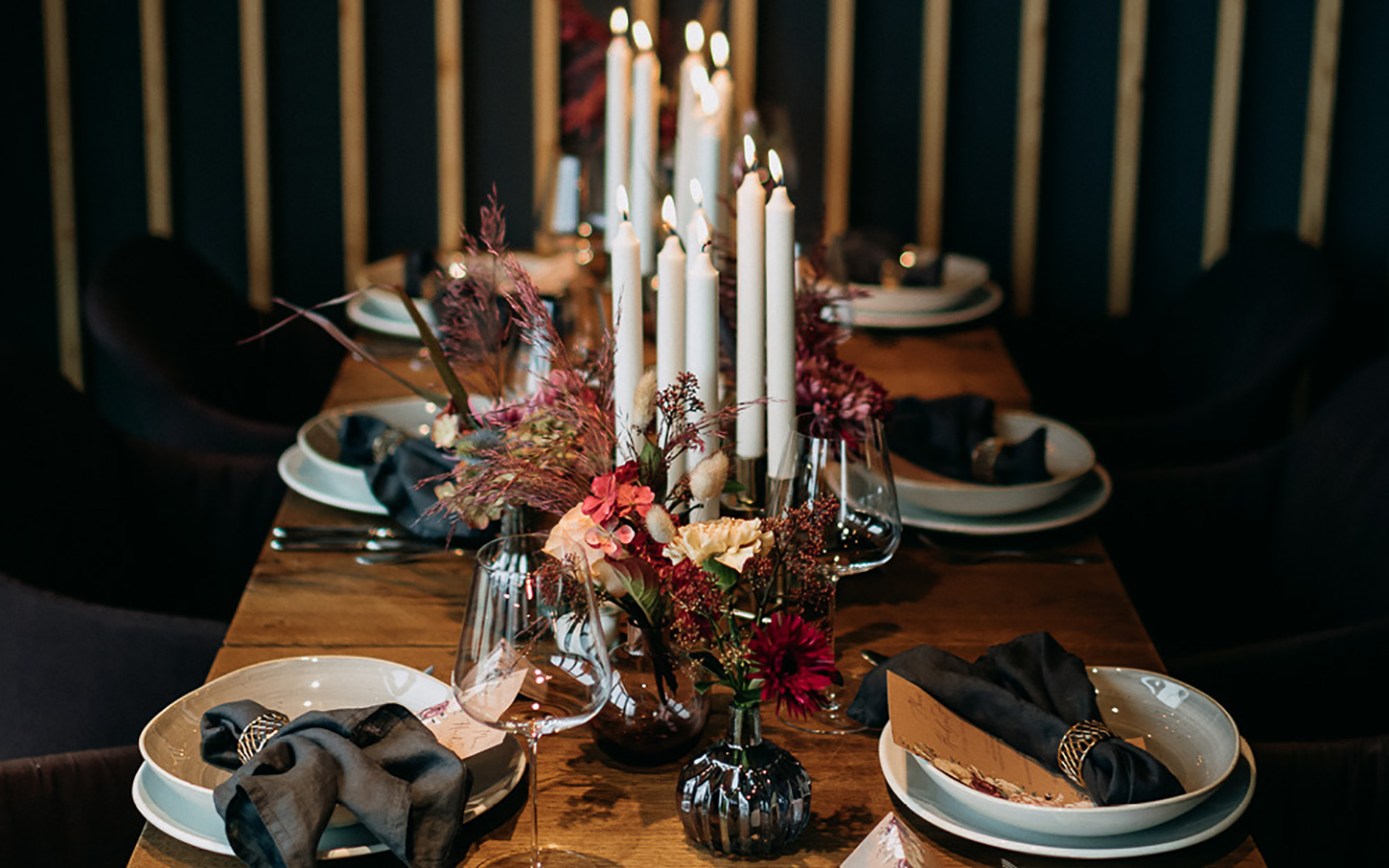 Ein stilvoll angerichteter Hochzeitstisch in klassisch, romantischem Stil. Die Farben sind in dunkleren Tönen gehalten und die Blumen rot, pink und hellbeige. 