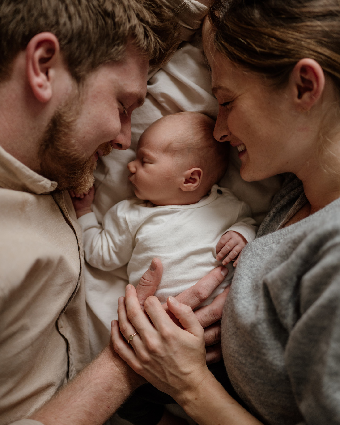 Eltern kuscheln mit Baby im Bett