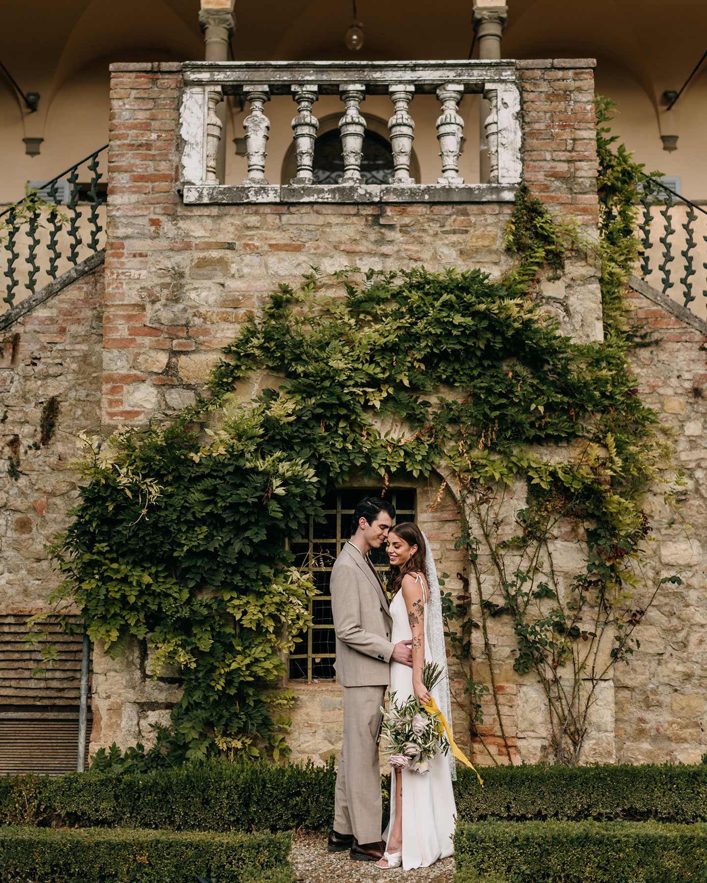 Das verliebte Hochzeitspaar steht vor der atemberaubenden Location und posiert für ein Fotoshooting. 