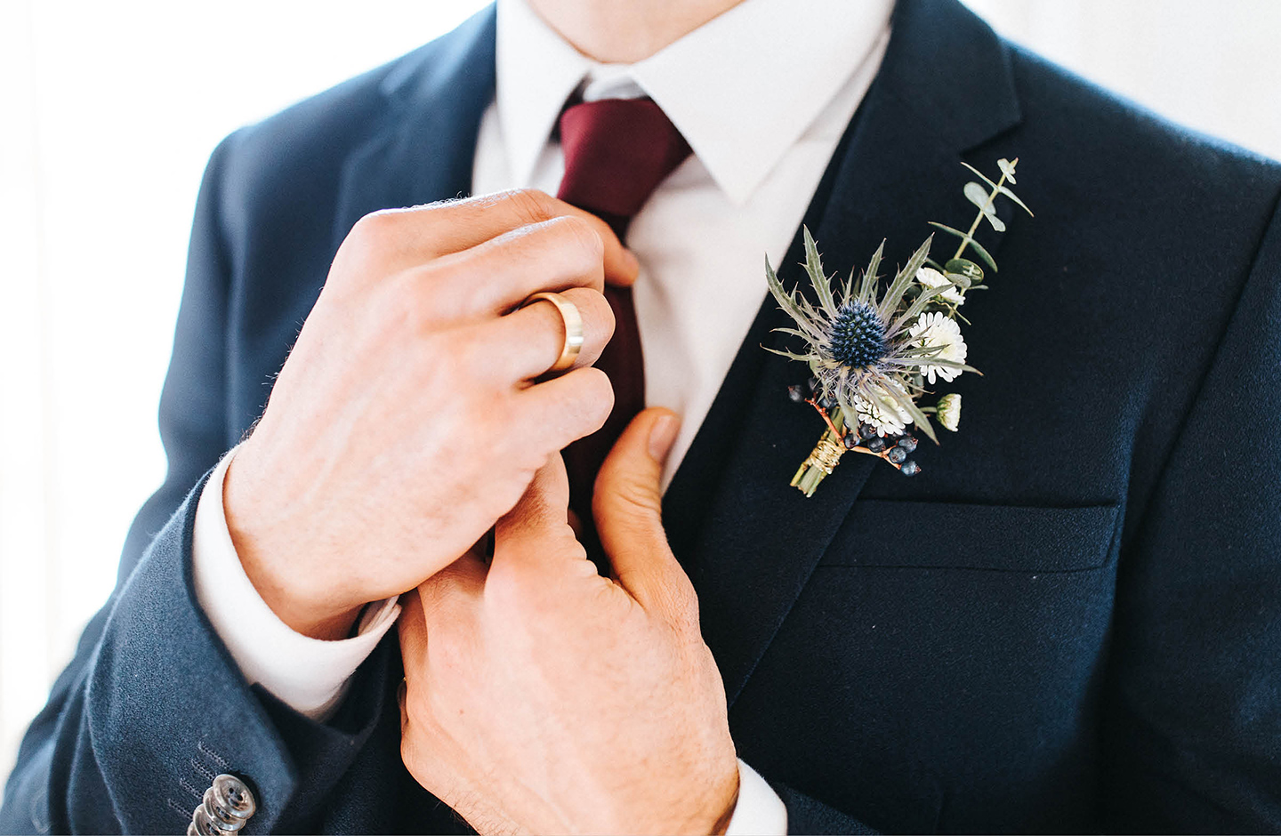 Nahaufnahme des Bräutigams. Der Bräutigam richtet seinen Schlips. Er trägt einen dunkelblauen Anzug