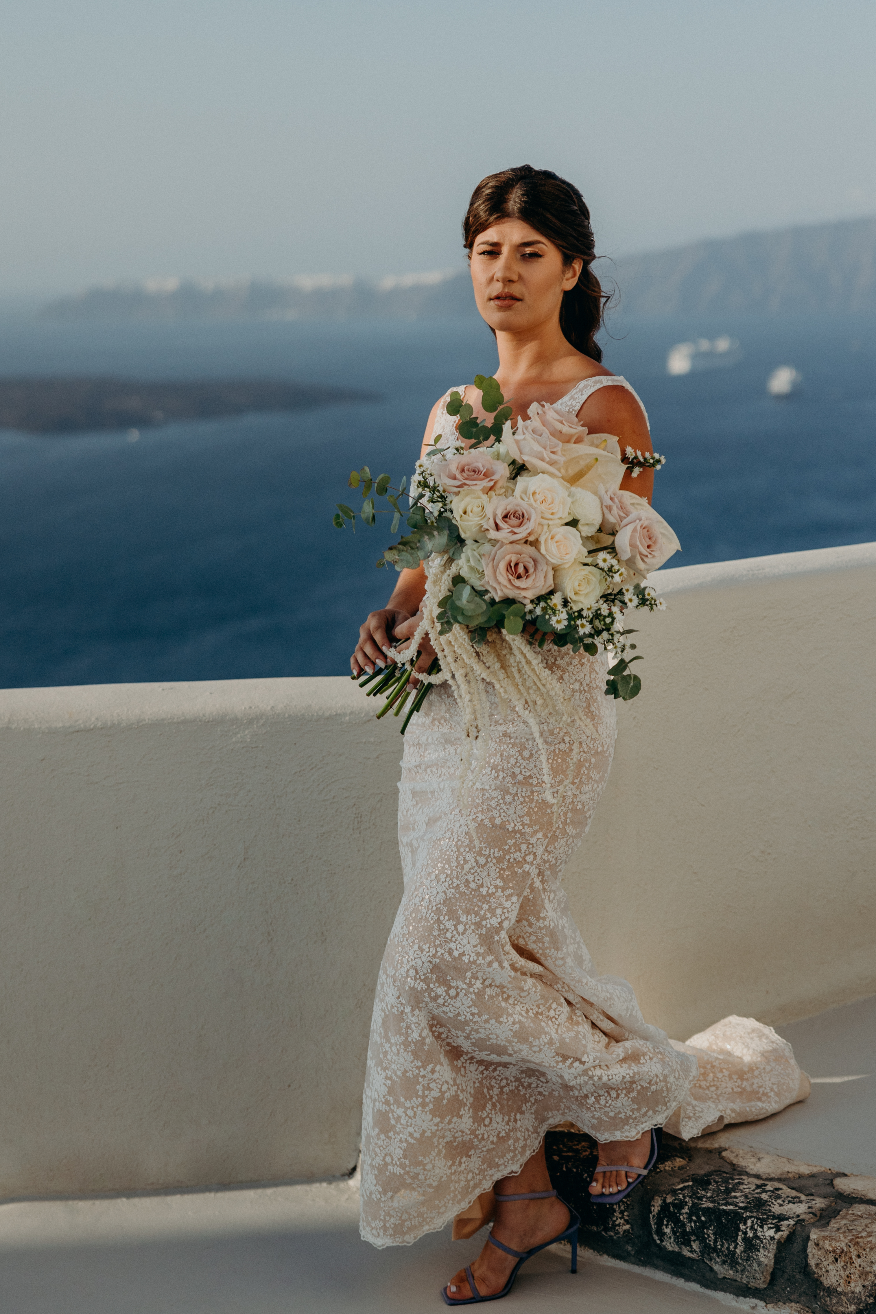 Die Braut trägt ein bodenlanges Kleid und einen Blumenstrauß mit pastellfarbenen Rosen.