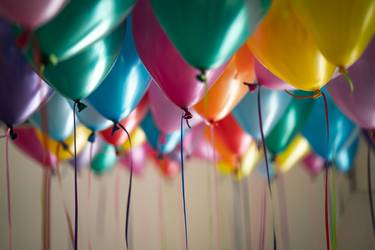 Viele mit Helium gefüllte bunte Luftballons die an der Decken hängen.