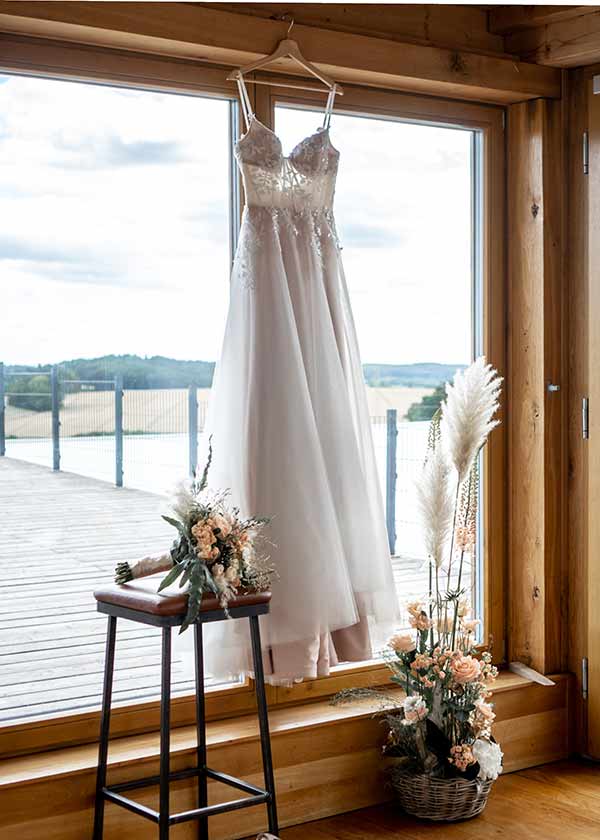 Brautkleid mit Transparenz hängt am Fenster.
