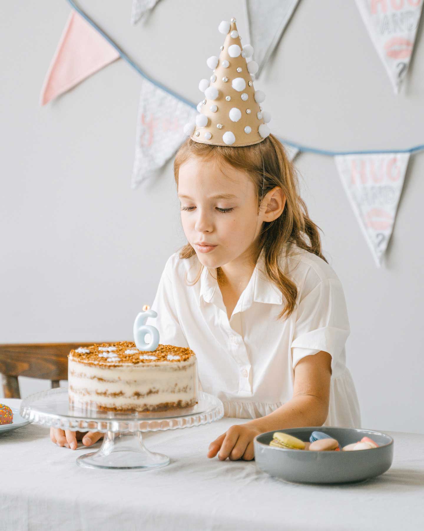 Mädchen bläst Kerze auf Kuchen aus