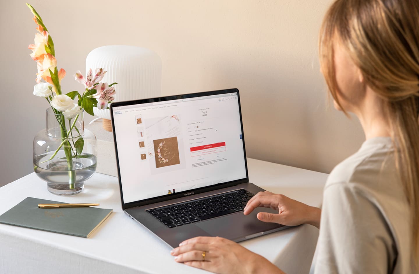 Junge Frau am Laptop bei der Gestaltung ihrer Hochzeitseinladungen