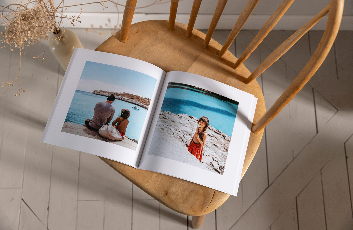 Fotobuch über einen Familenurlaub liegt aufgeschlagen auf einem Stuhl
