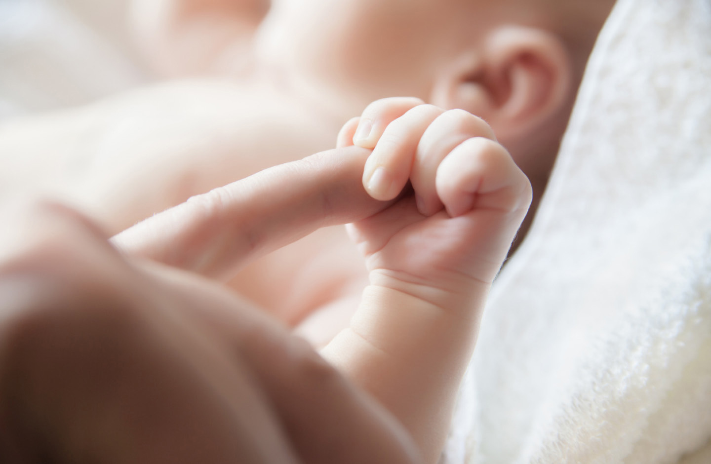 Baby mit russischem Mädchennamen umfasst mit der linken Hand den Finger der Mutter