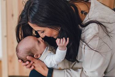Baby auf dem Arm der Mutter greift nach Zeigefinder des Vaters