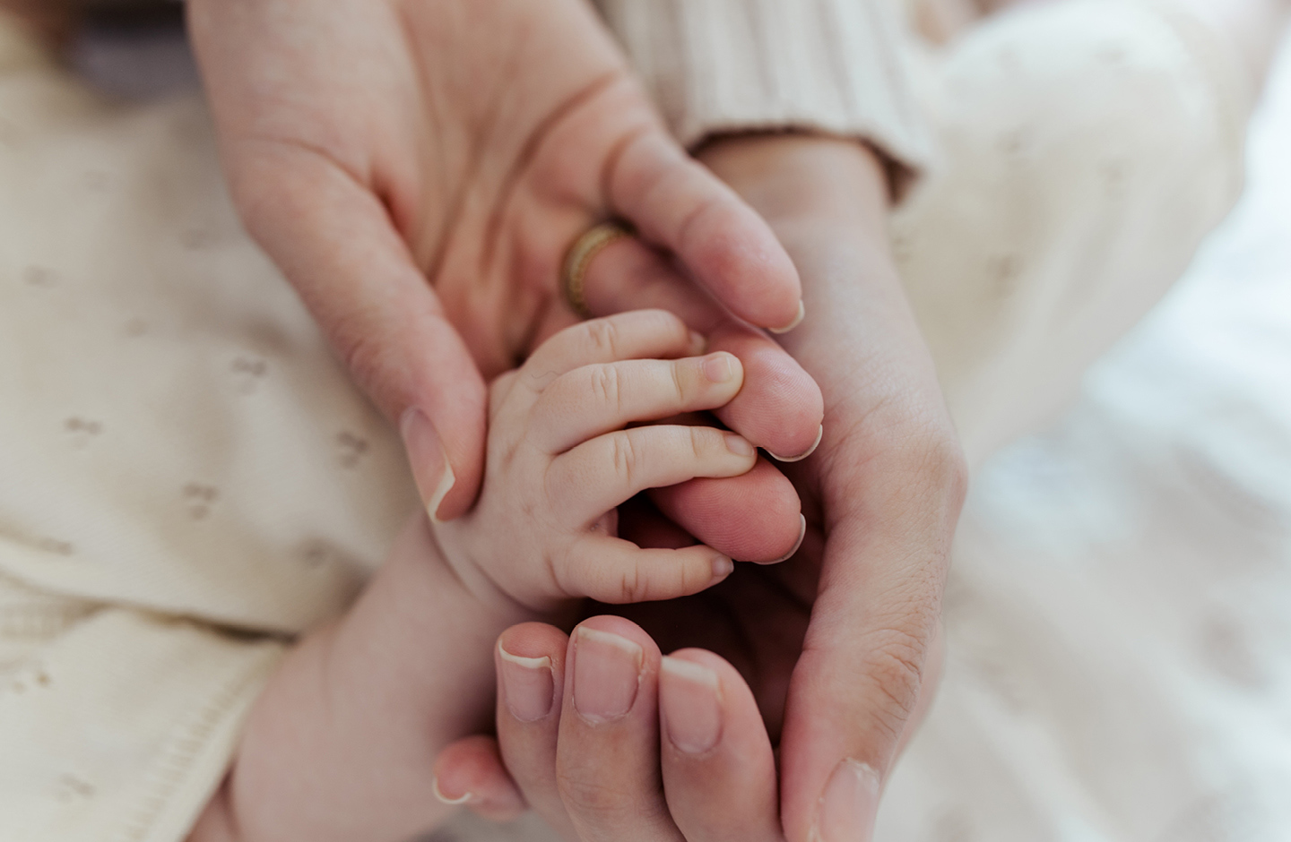 Frischgebackene Eltern halten Hand ihres Babys nach der Geburt mit Geburtsplan.