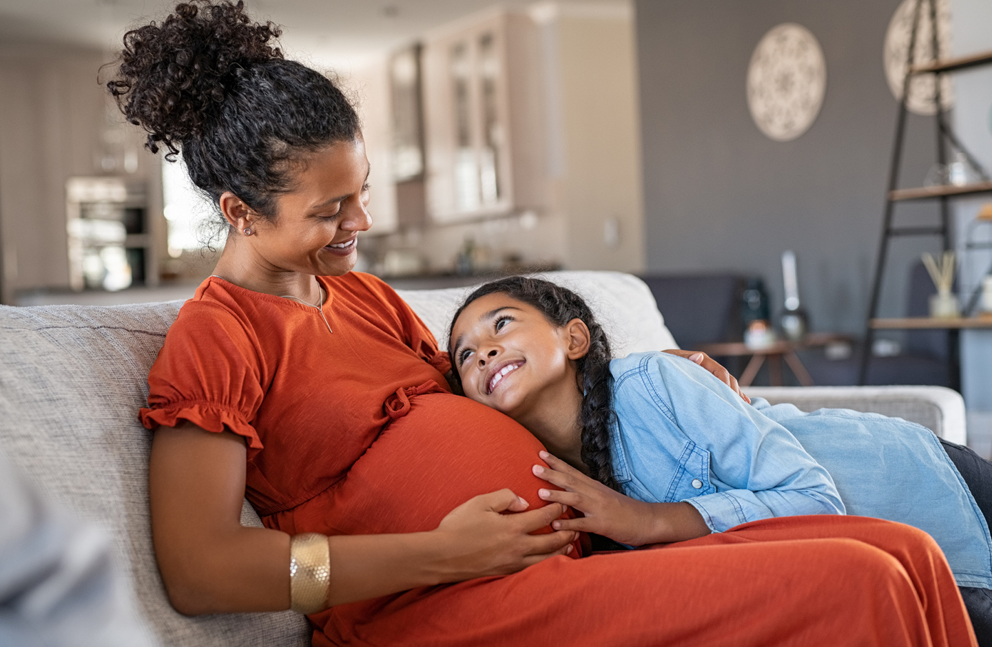 1. Trimester - Tochter streichelt Babybauch der Mama