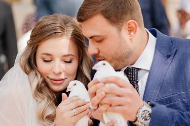 Braut und Bräutigam halten weiße Brieftauben in der Hand.