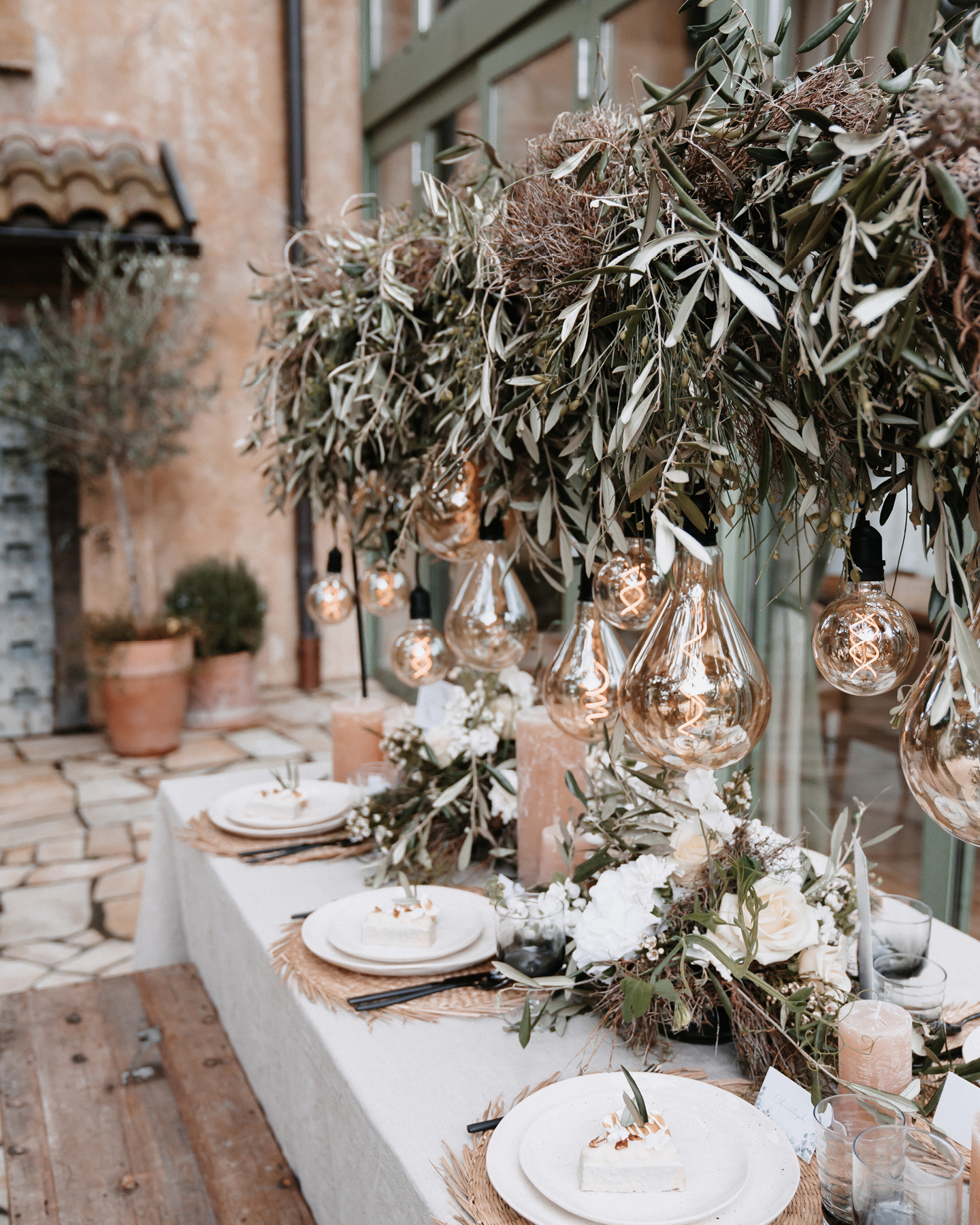 Die Hochzeitstafel ist dekoriert mit Euklayptuszweigen, weißen Blüten und einer Lichterkette im Boho Stil.