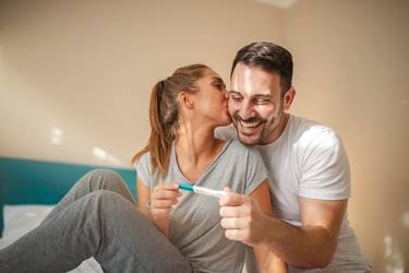 Paar betrachtet glücklich einen Schwangerschaftstest