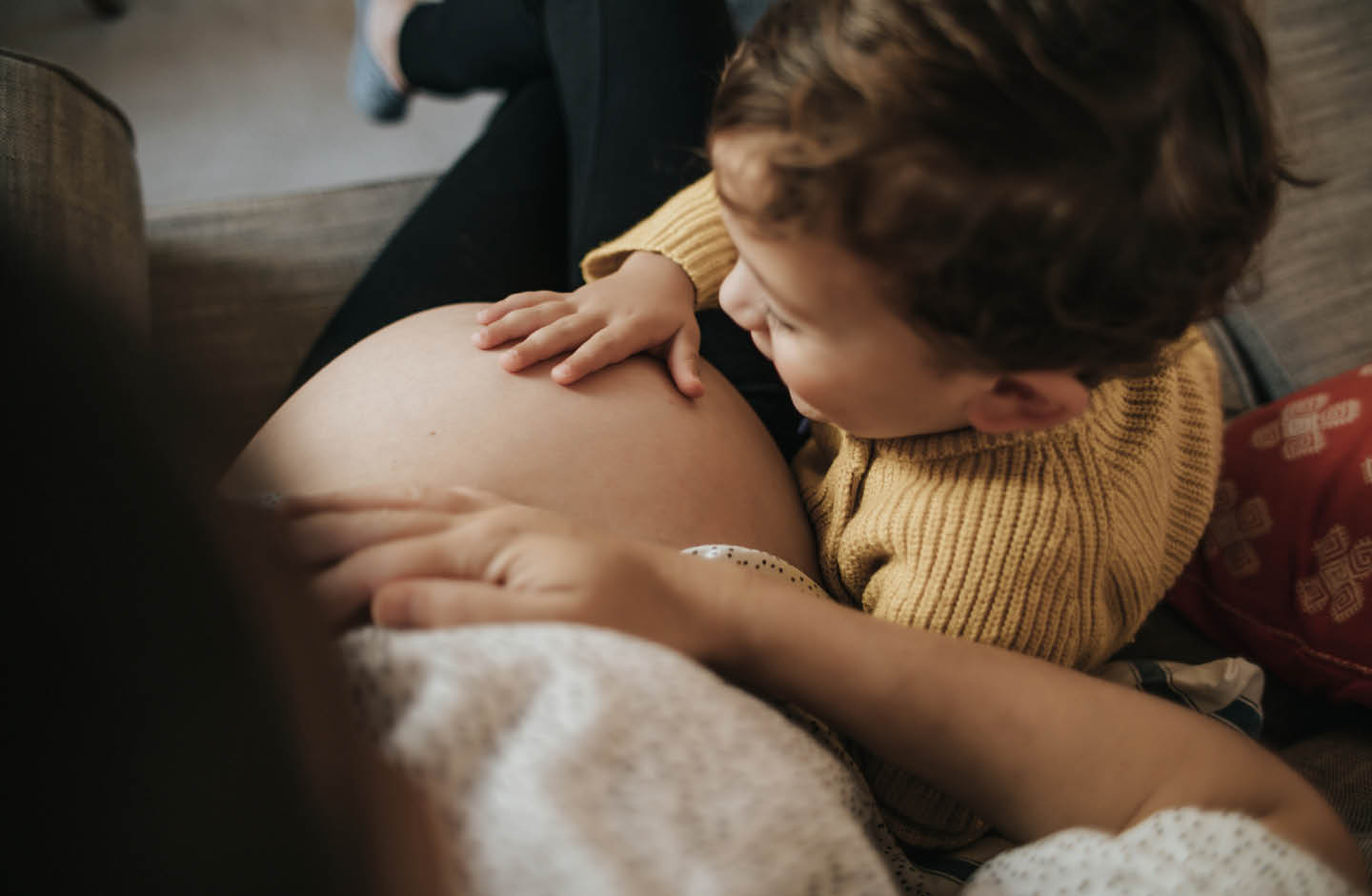 Kleinkind streichelt über den Babybauch der Mama