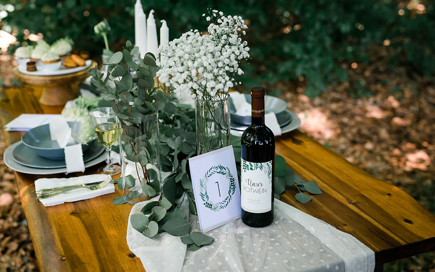 Tischdeko Hochzeit: Ein Hochzeitstisch im Greenery Look: Eukalyptus und Schleierkraut auf der rustikalen Tafel geben ein harmonisches Bild.