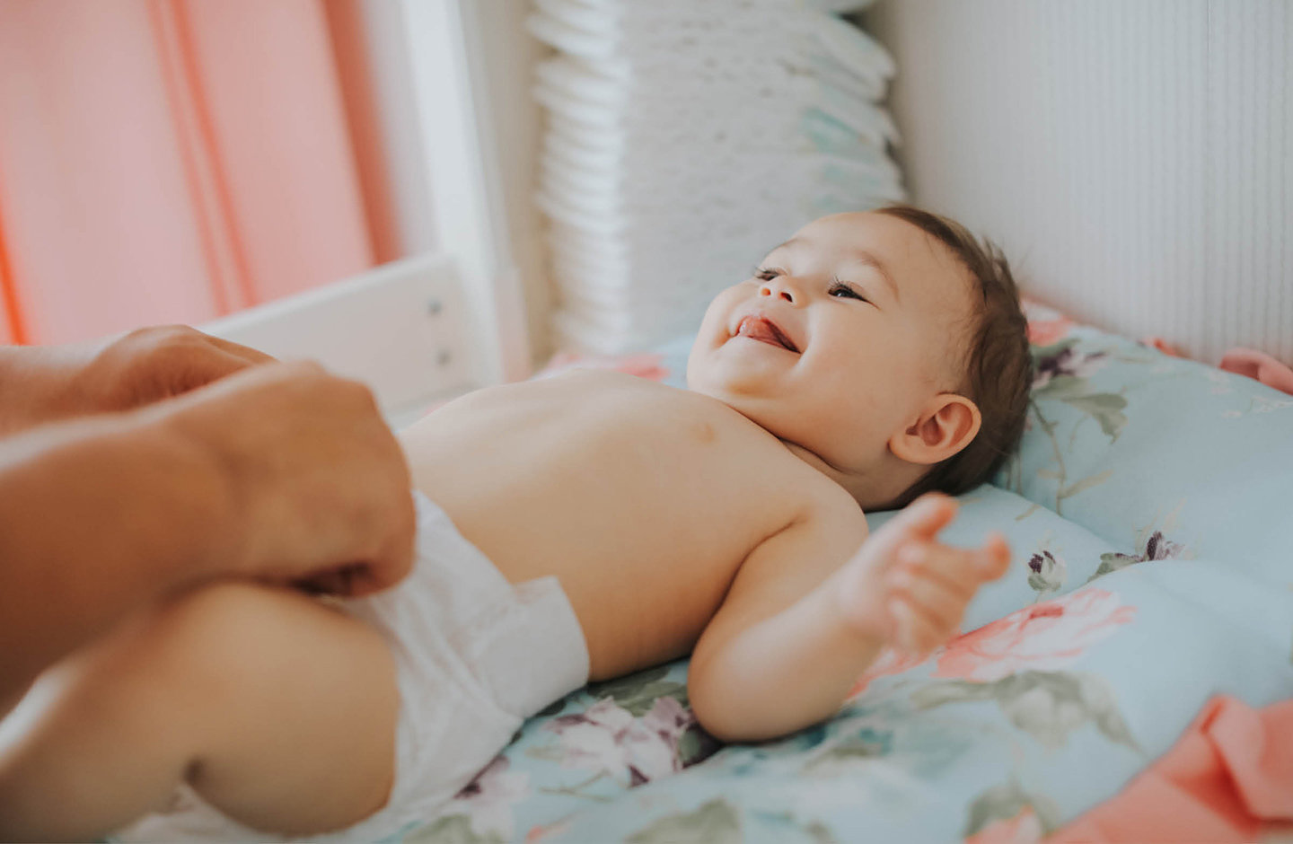 Baby liegt auf em Wickeltisch, streckt die Zunge raus und wird gewickelt.