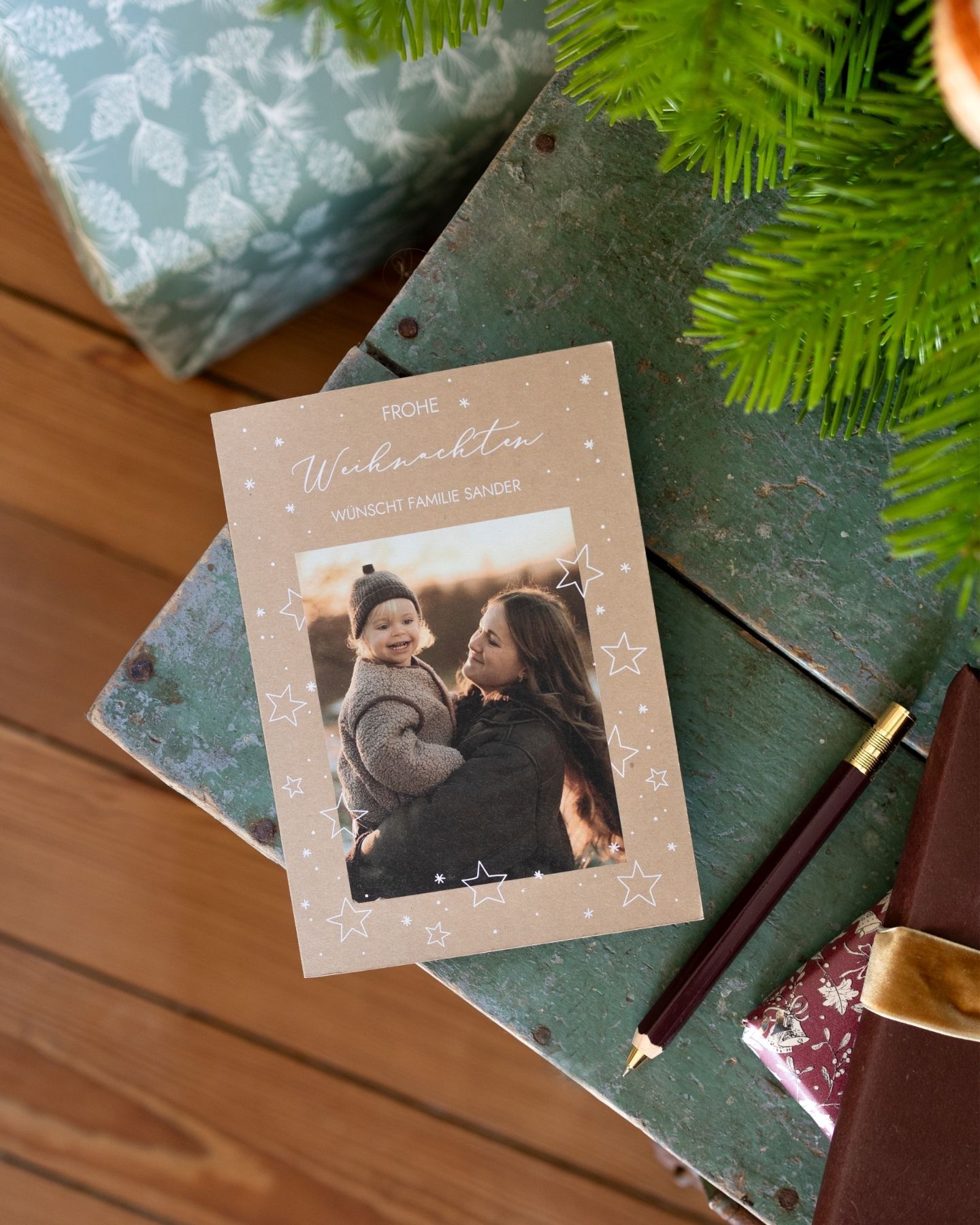 Weihnachtskarten werden mit Stift beschrieben. Mädchen in roten Pullover liest Weihnachtskarte.