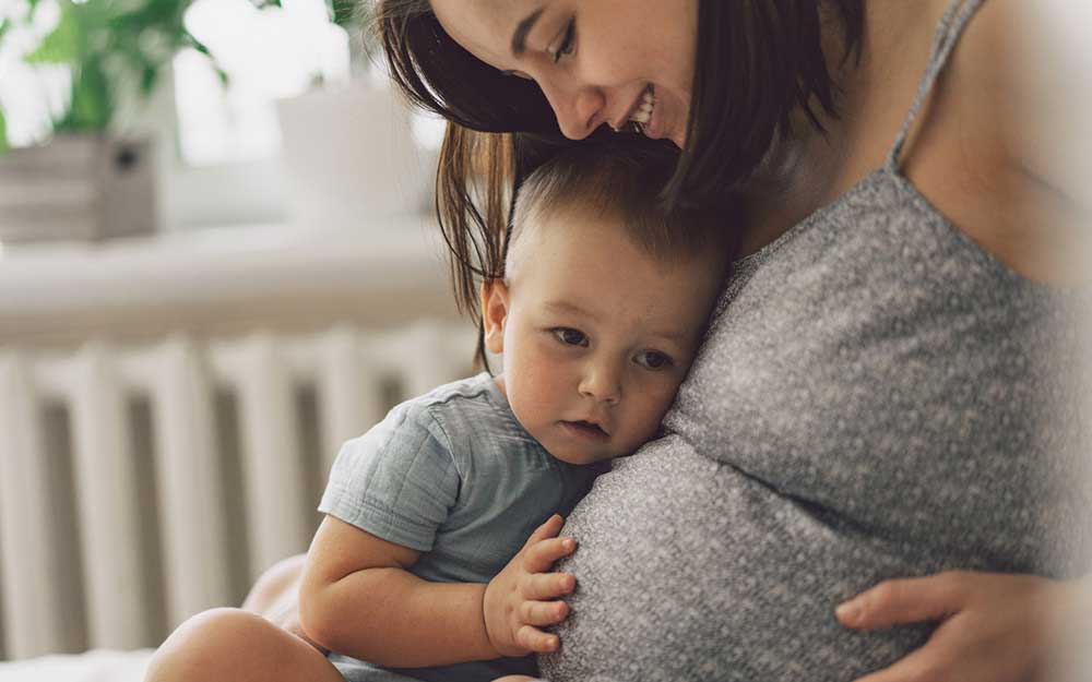 Schwangere drückt kleinen Sohn an ihren Bauch