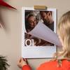 Fotokalender hängt an der Wand. Frau blättert die erste Seite des Kalenders um.