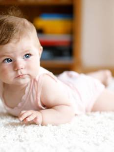 Baby in Bauchlage auf dem Teppich versucht zu robben