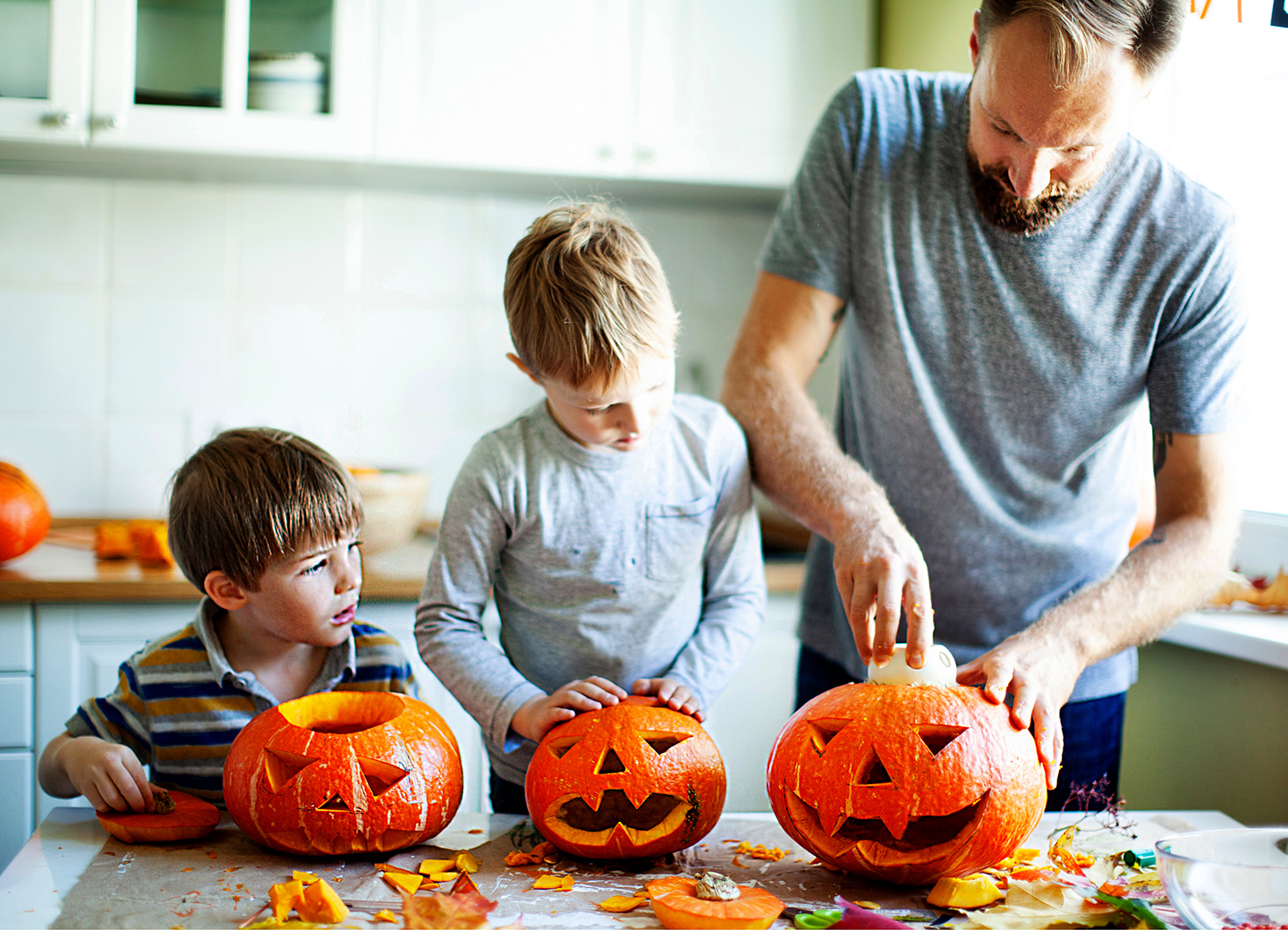 Papa und Söhne schnitzen Kürbisse für Halloween Party