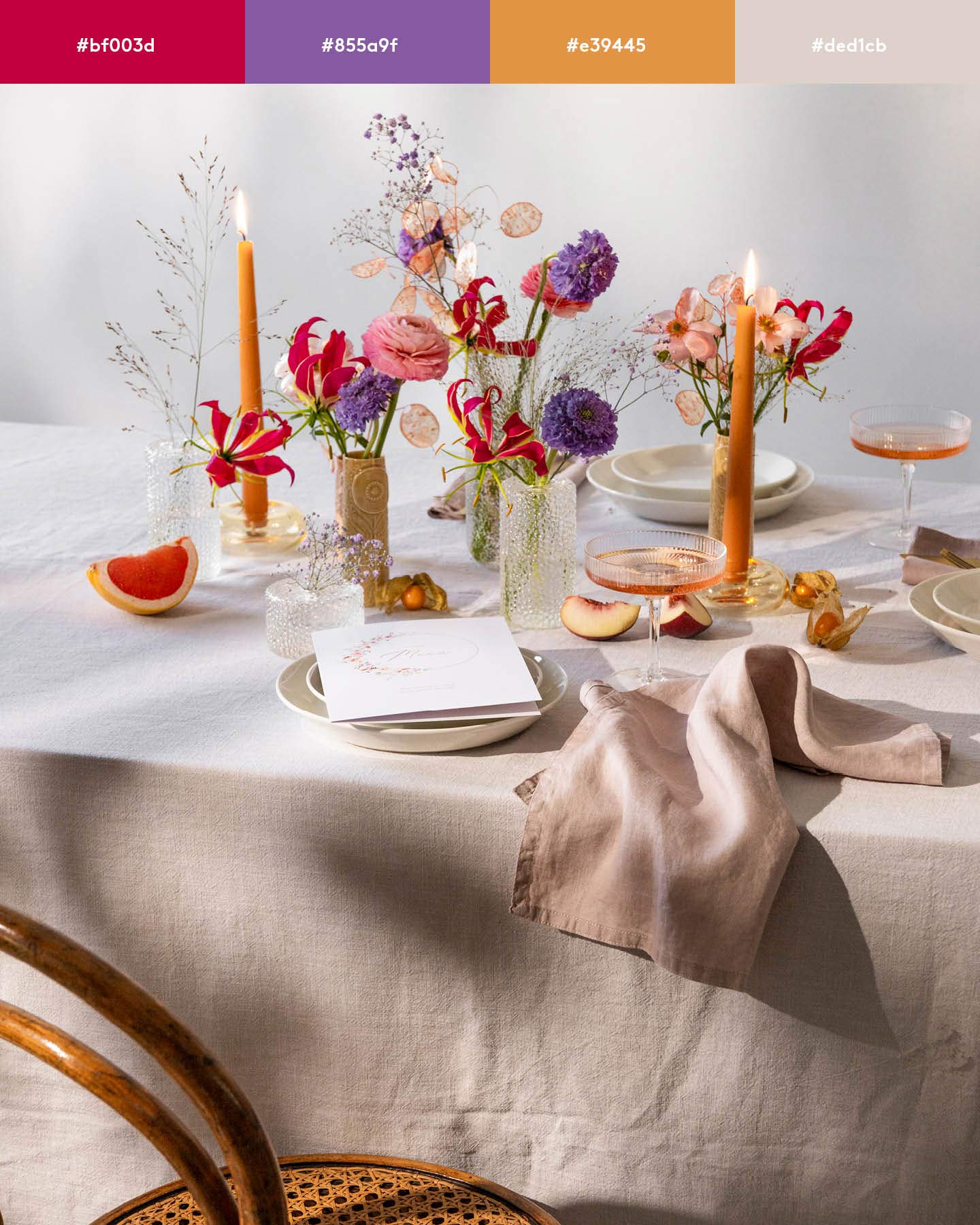 Eine Hochzeitstafel ist mit bunten Blumen in Orange, Rot und Lila dekoriert.