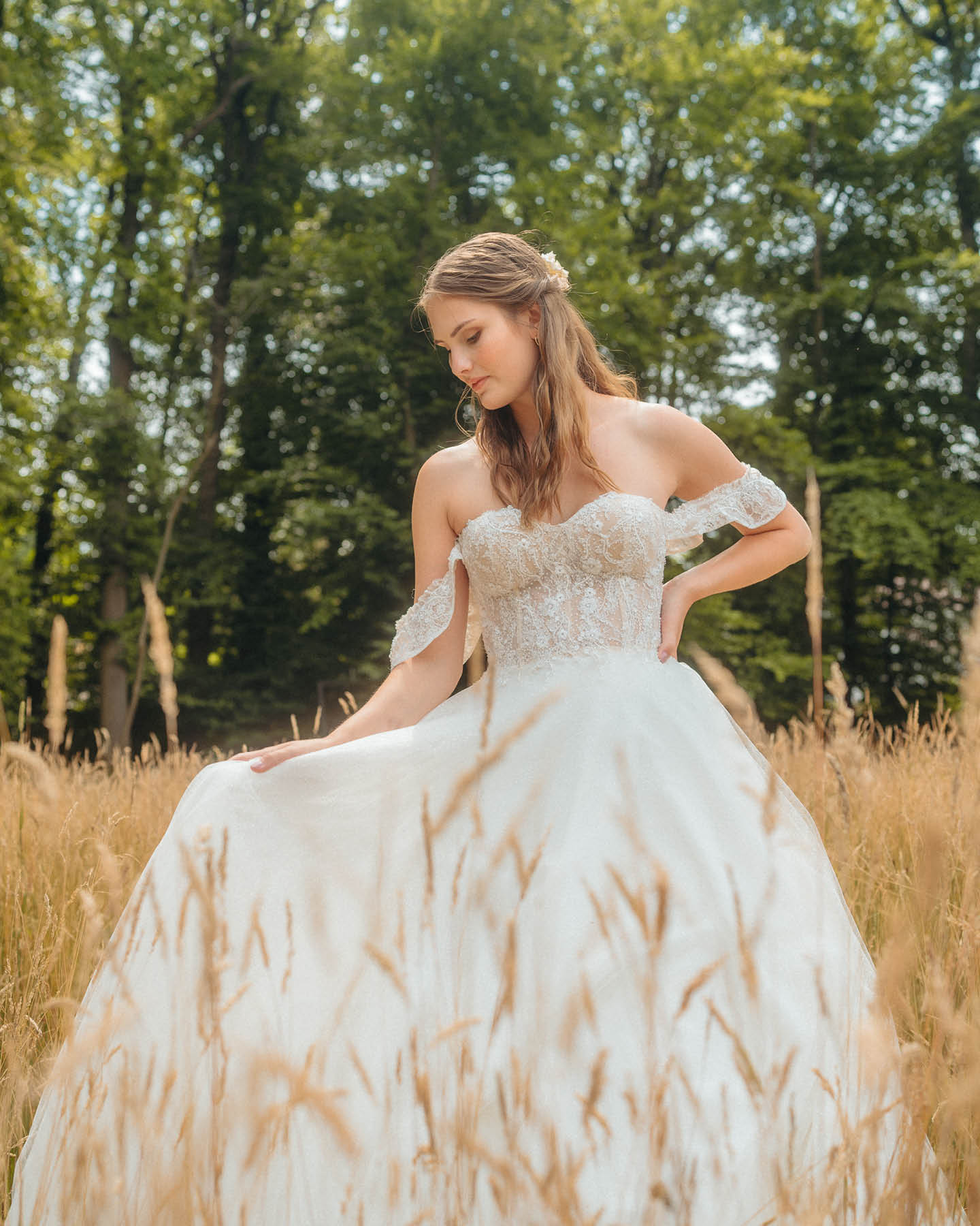 Frau im Brautkleid steht in einem Feld.