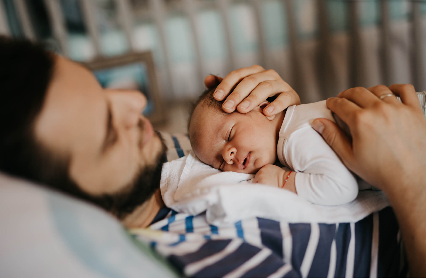 Junger Vater küsst neugeborenes Baby